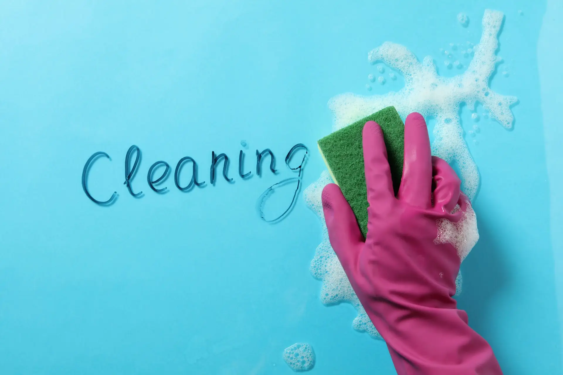 Hand cleaning a blue surface with a sponge